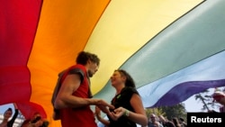 Serbia – Gay rights activists dance under a rainbow flag during a Pride march in Belgrade, September 28, 2014